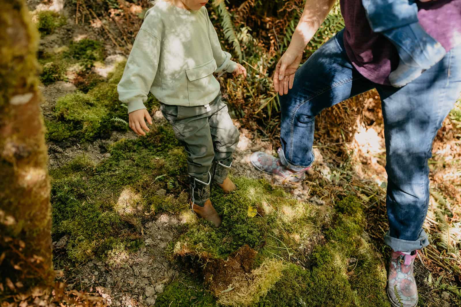 Adult guiding child on forest path at Hidden Meadow School