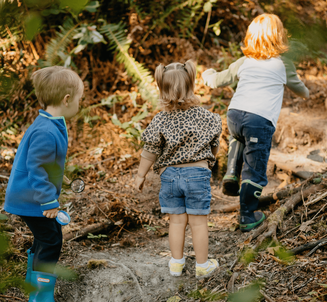 Children running through the forest on a trail adventure at hidden meadow school