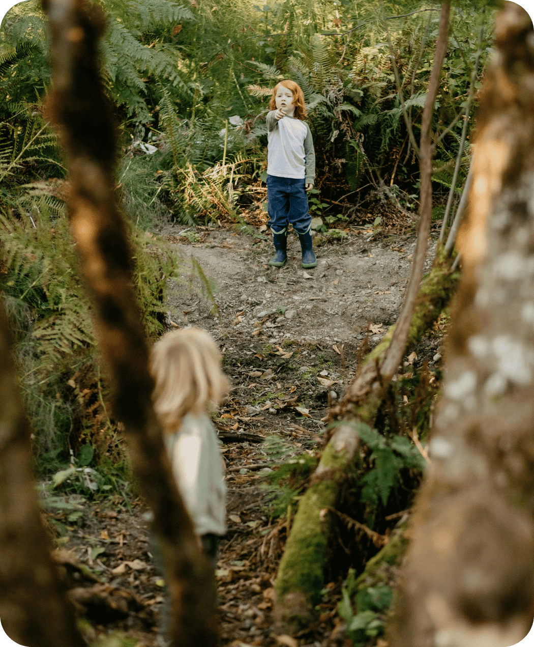 Children playing in the trails of Hidden Meadow School. One child pointing to the other