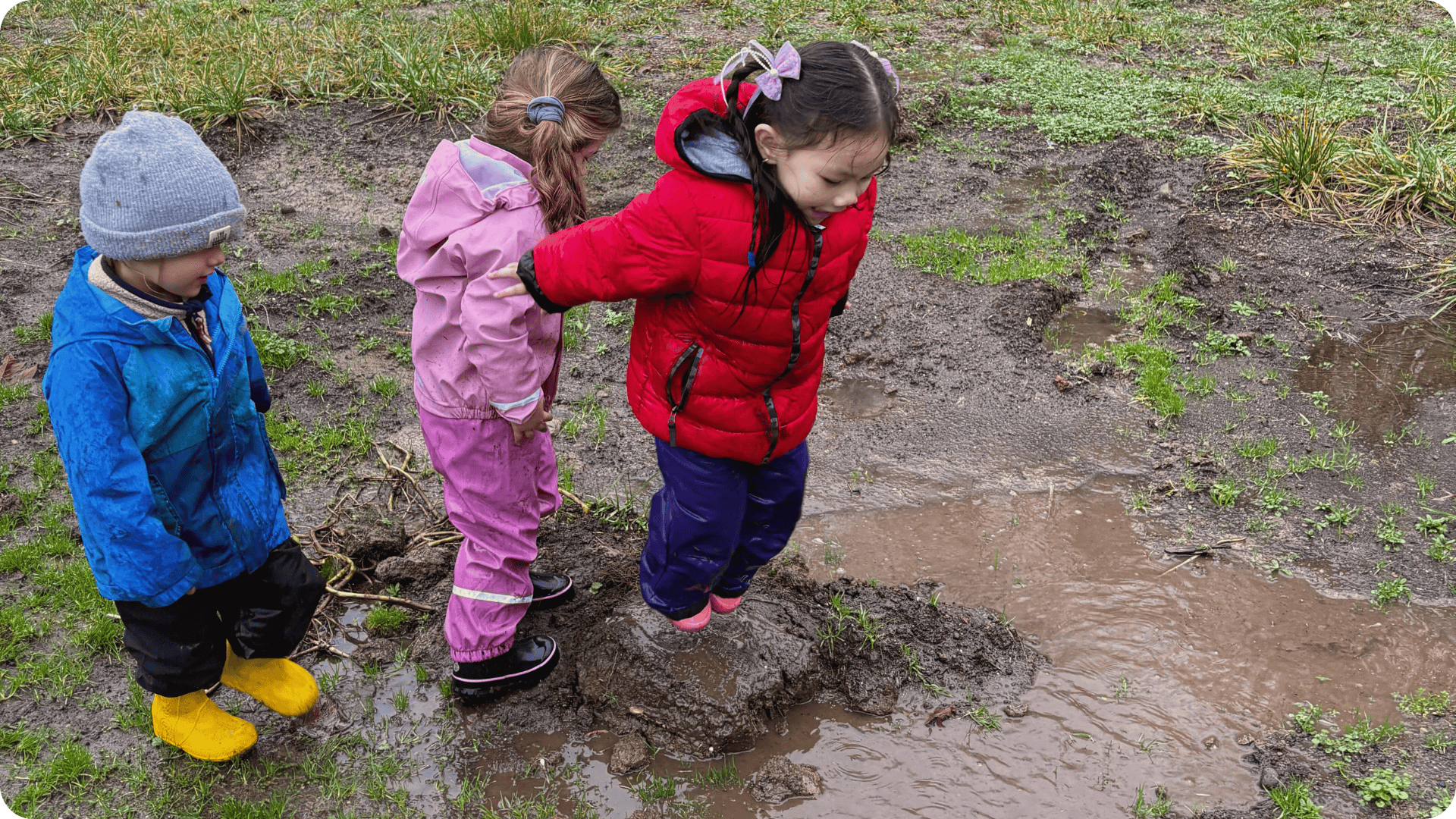 Child jumping into a puddle at Hidden Meadow School