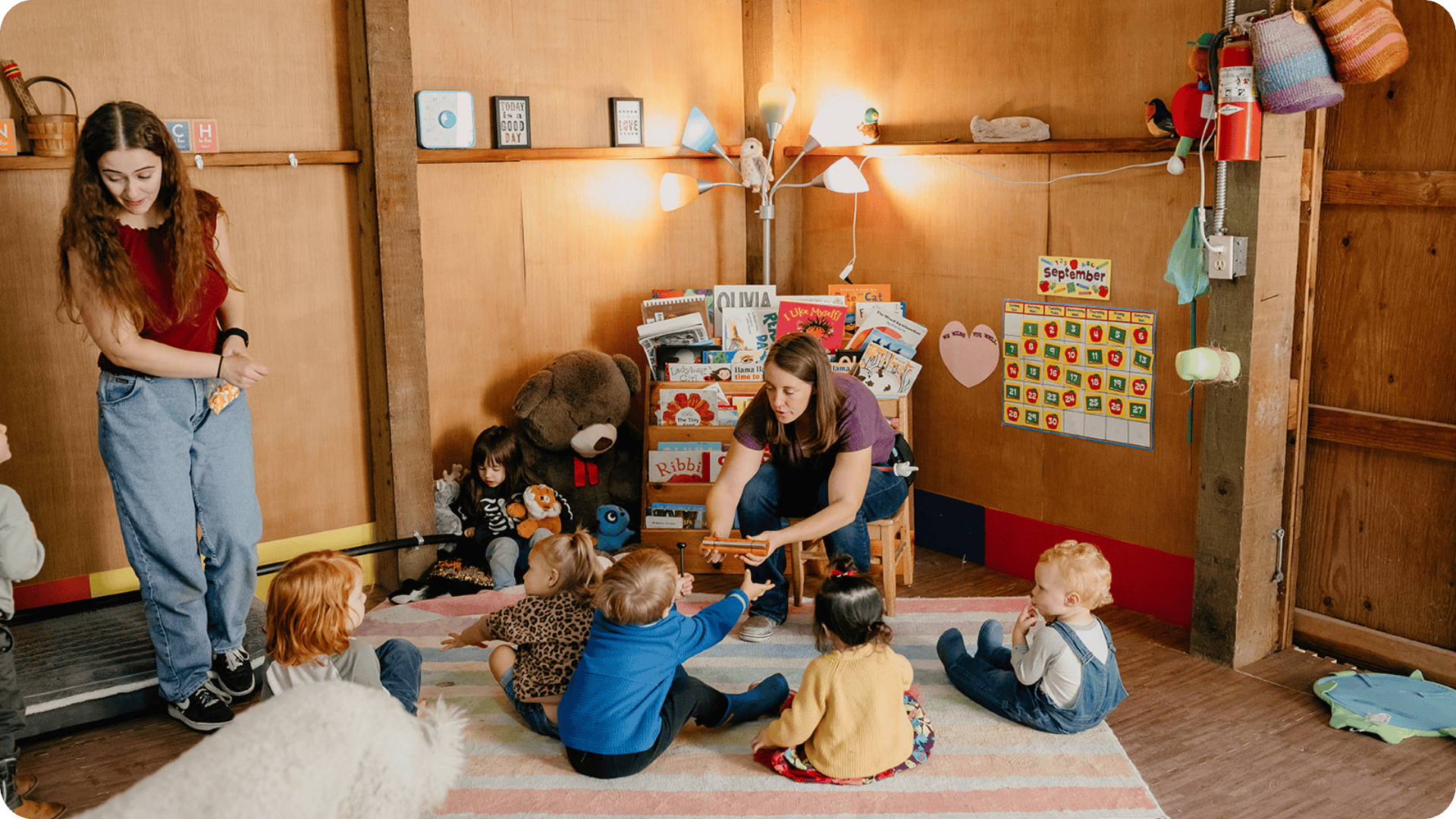Molly showing instrument to children sitting around on the rug at Hidden Meadow School