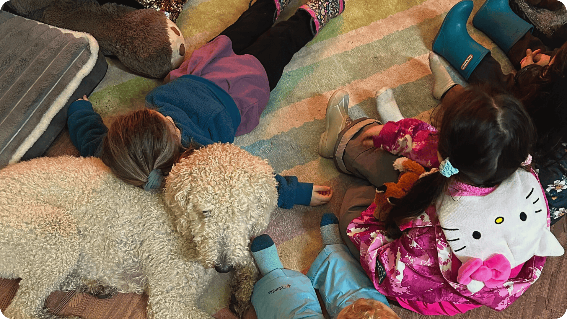 Child laying against Wilma surrounded by other children at Hidden Meadow School